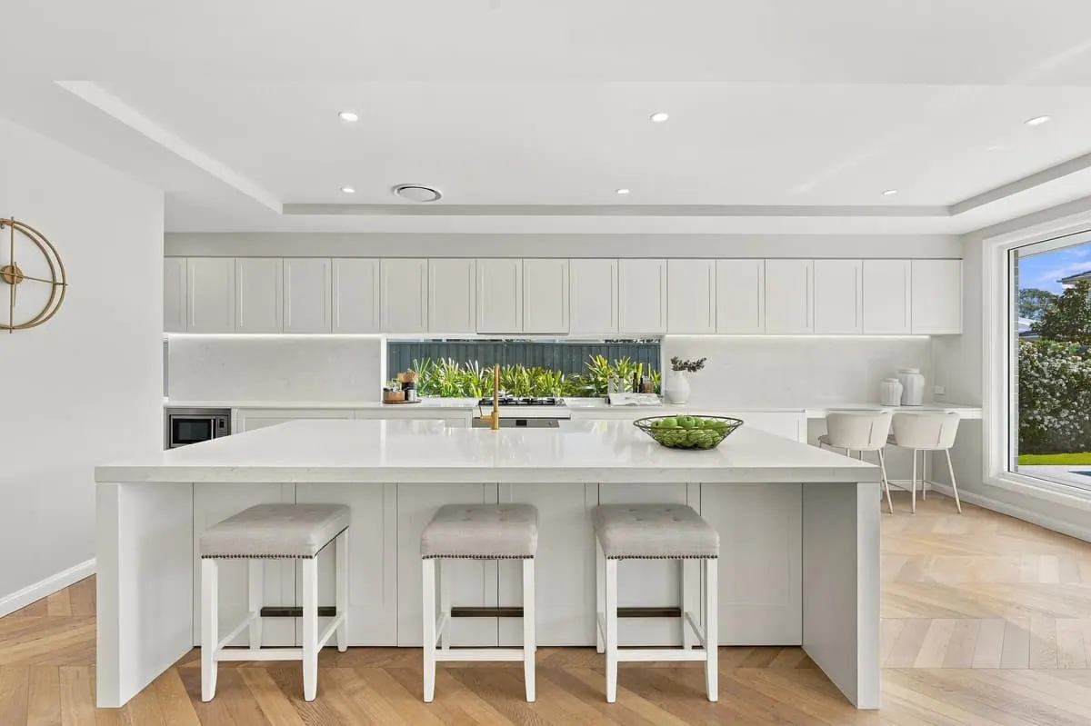 White kitchen with island bench and pendant lights
