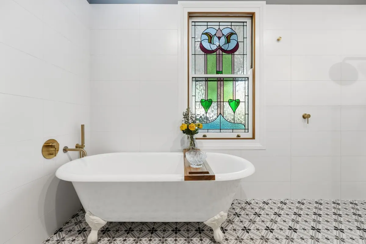 Clawfoot bath beneath a stained-glass window