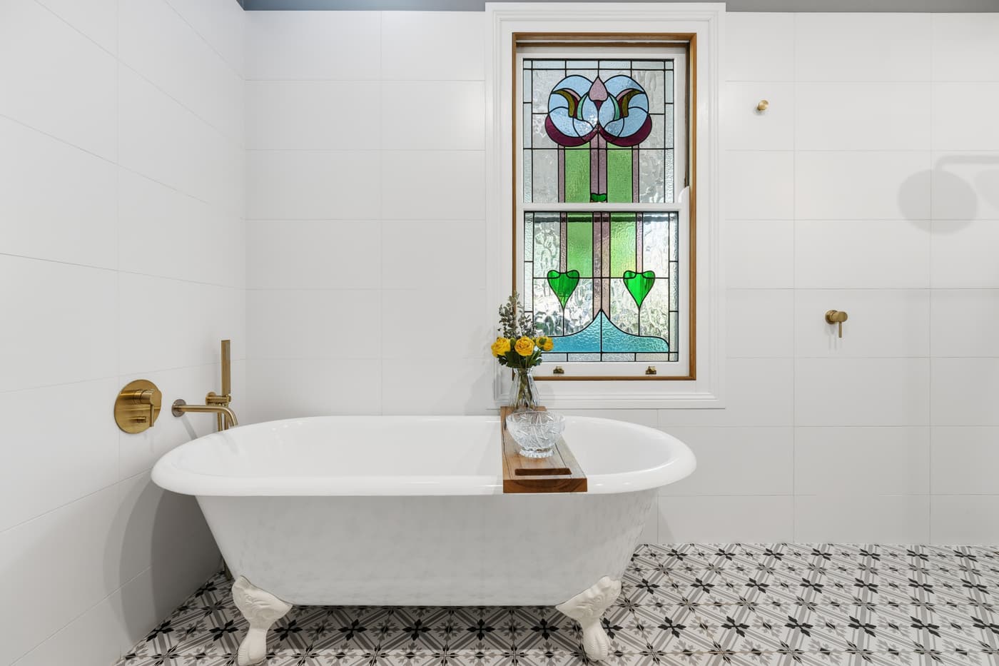 Clawfoot bath beneath a stained-glass window